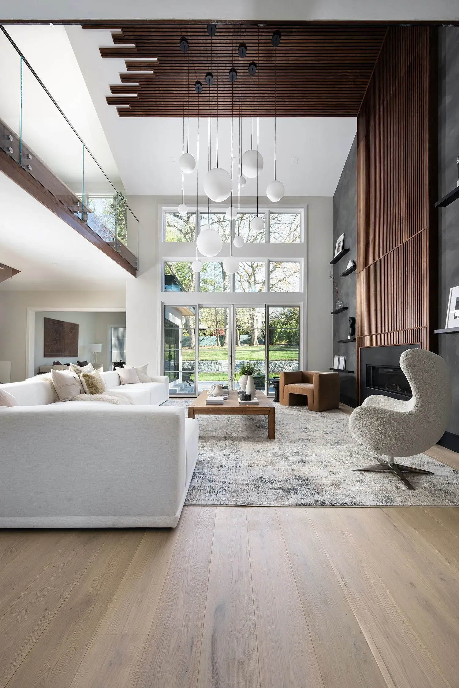 Spacious living room with a double-height ceiling, large windows, and a modern white sofa.