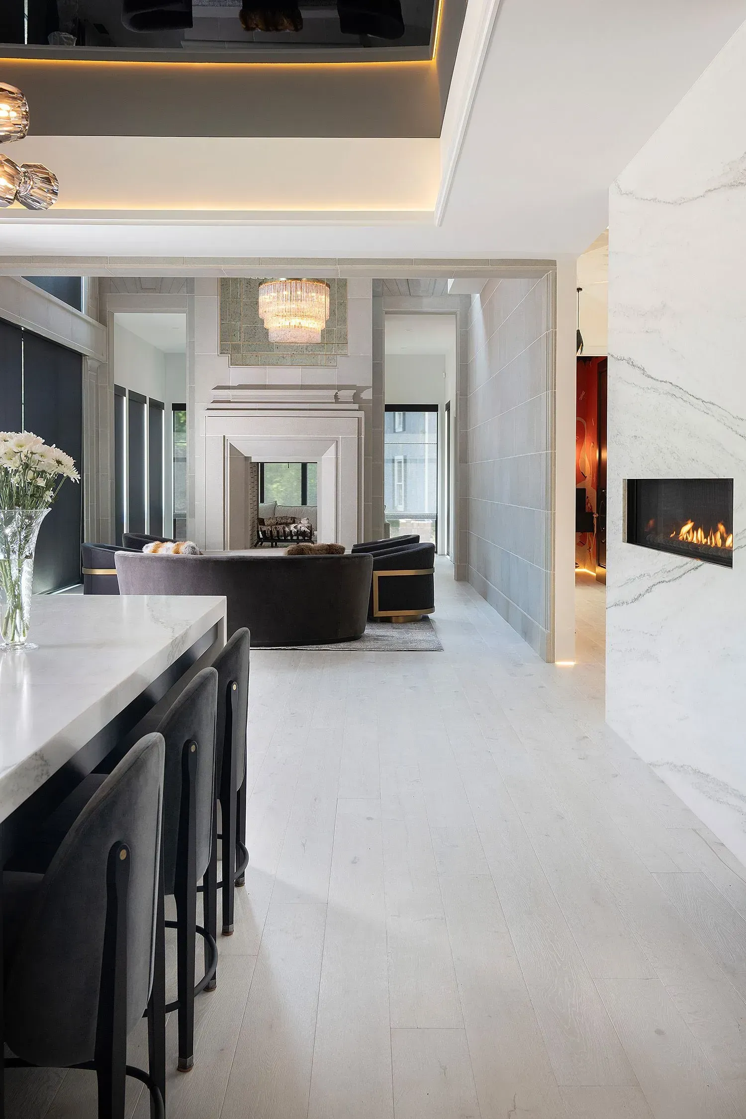 Modern living room with marble fireplace, kitchen island, and dark gray seating.
