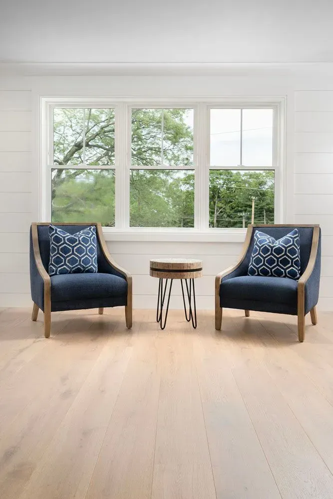 Two navy blue chairs with patterned pillows and a small table in front of a window.