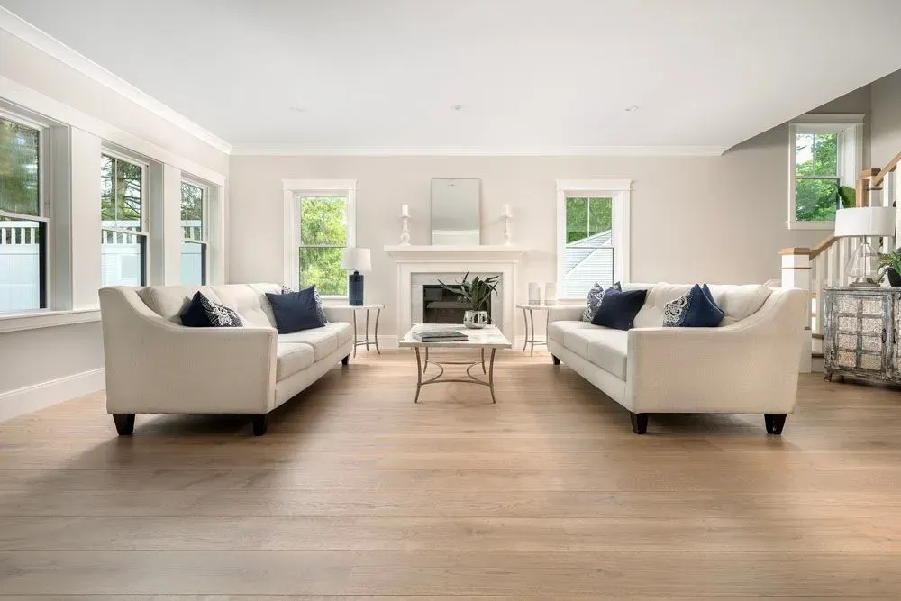 Light-filled living room with two cream sofas, a fireplace, and hardwood floors.