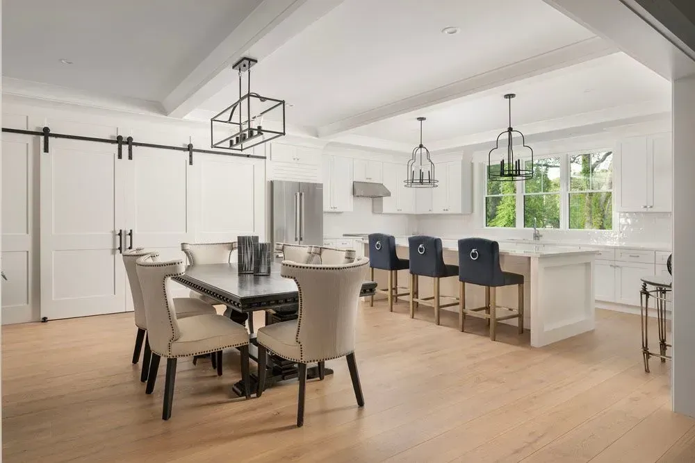 Bright kitchen and dining area with light wood floors, white cabinets, and black accents.