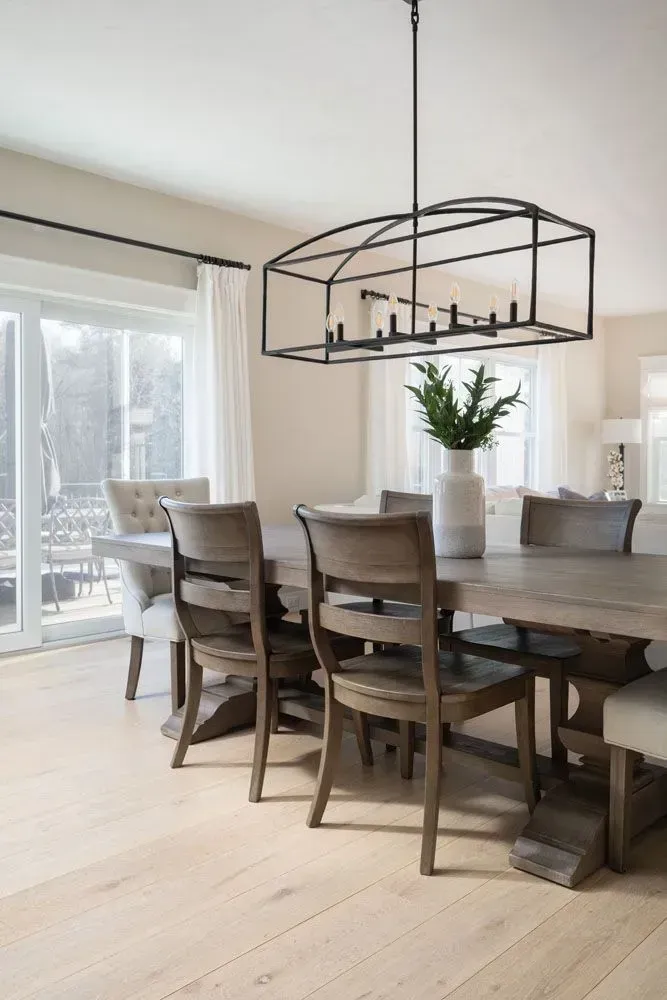 Dining room with wooden table and chairs, a large chandelier, and sliding glass doors.