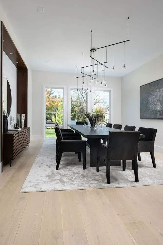 Modern dining room with a long black table, black chairs, and a geometric chandelier.