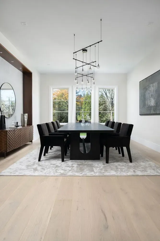 Elegant dining room with a large black table, chairs, and a modern chandelier.
