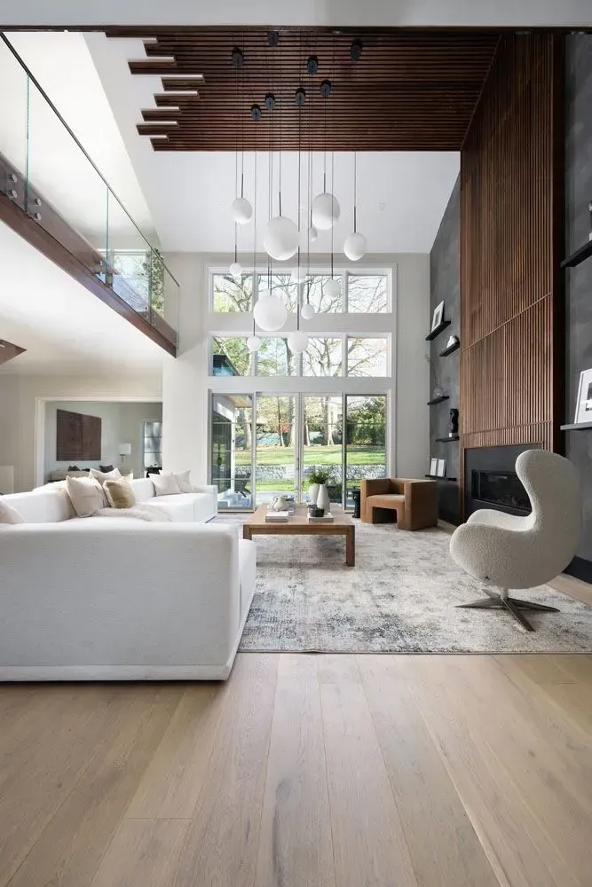 Modern living room with white sectional sofa, large windows, and wooden accents.
