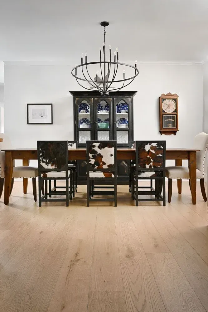 Dining room with a table, chairs, china cabinet, and chandelier. Cowhide-covered chairs.