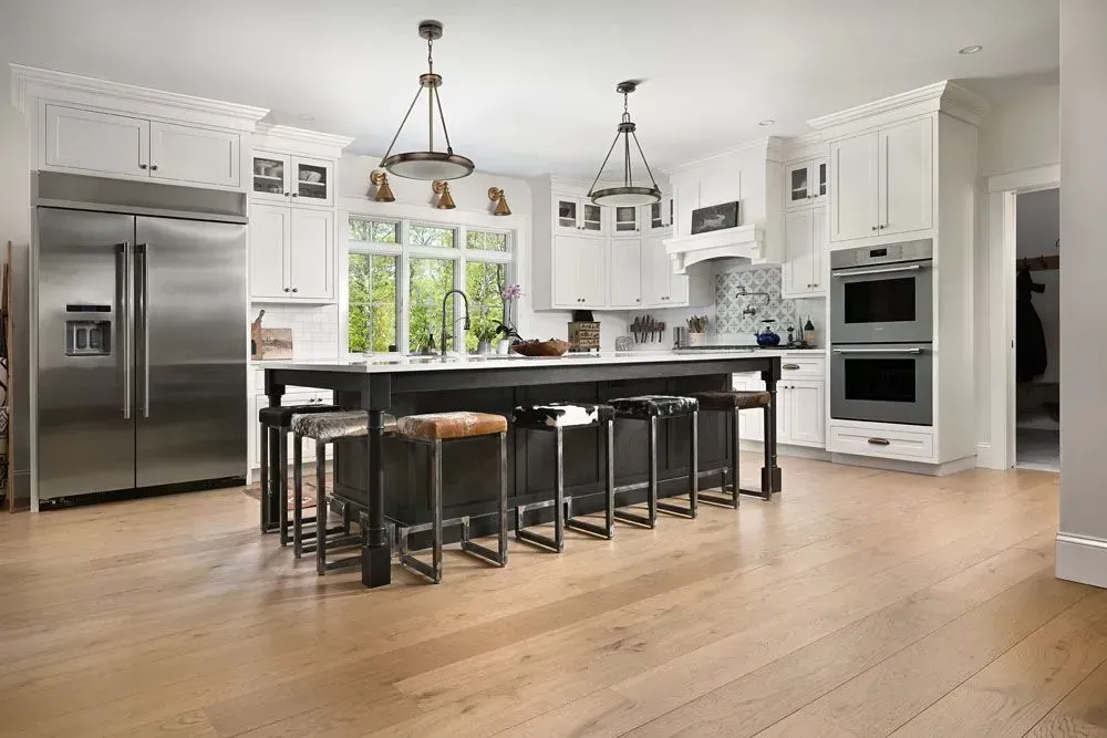 Spacious white kitchen with black island, stainless steel appliances, and hardwood floors.