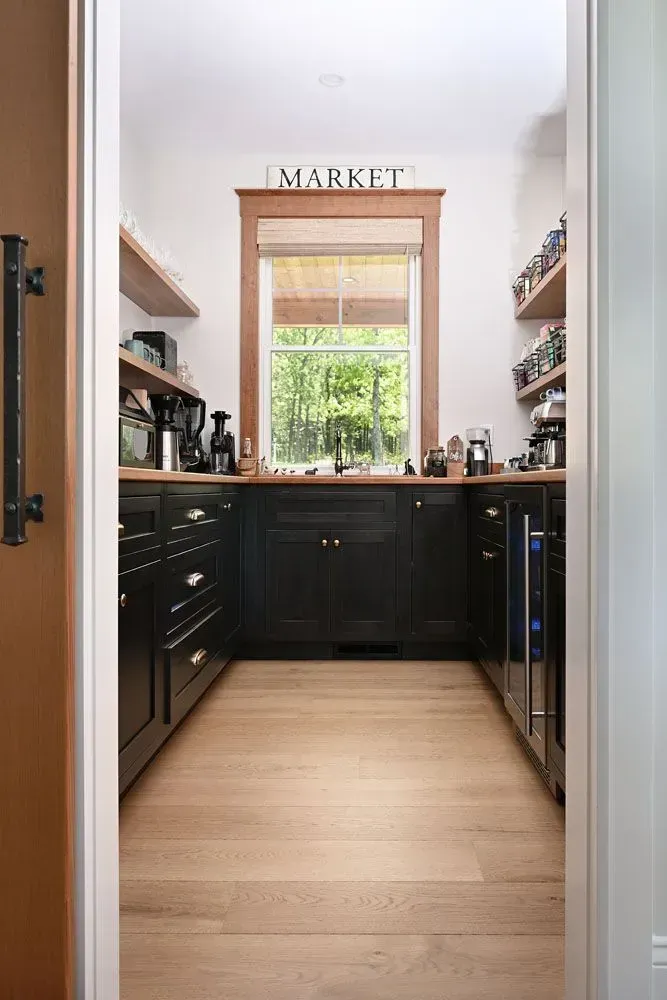View of a pantry with black cabinets, wooden shelves, window, and 
