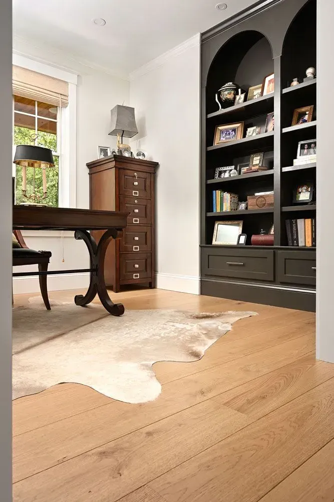 Home office with wood floors, a desk, a bookshelf, and a faux cowhide rug.