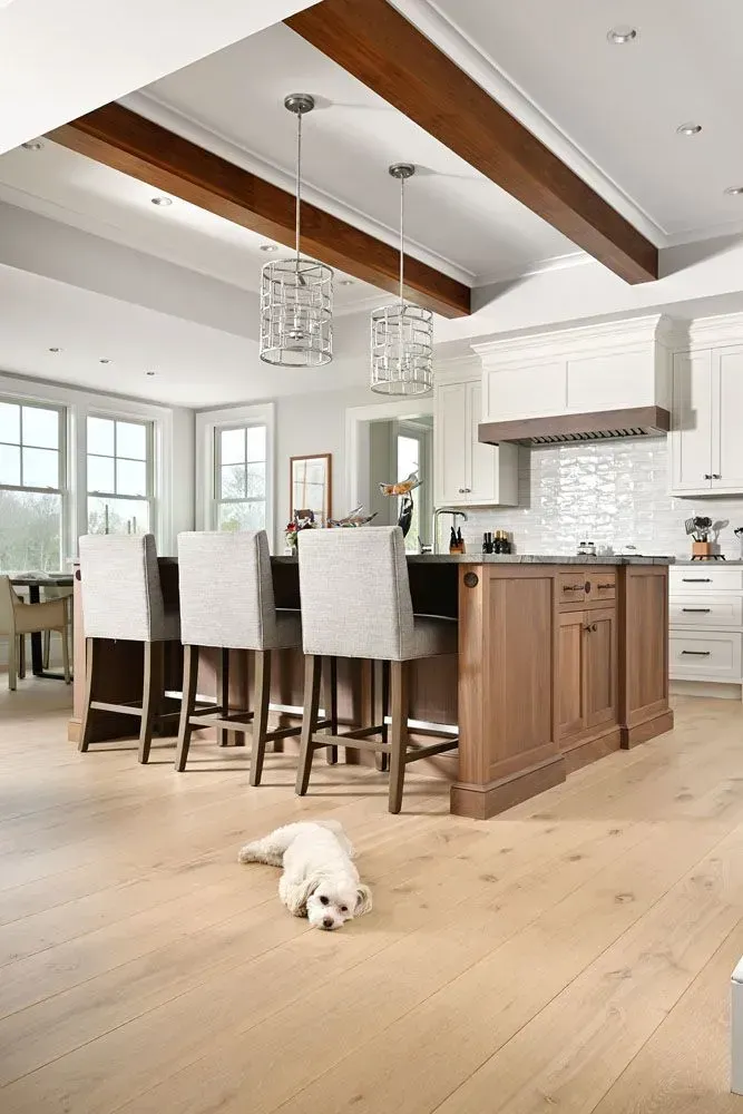 Cozy kitchen with a wood island, white cabinetry, and a fluffy white dog on the light wood floor.