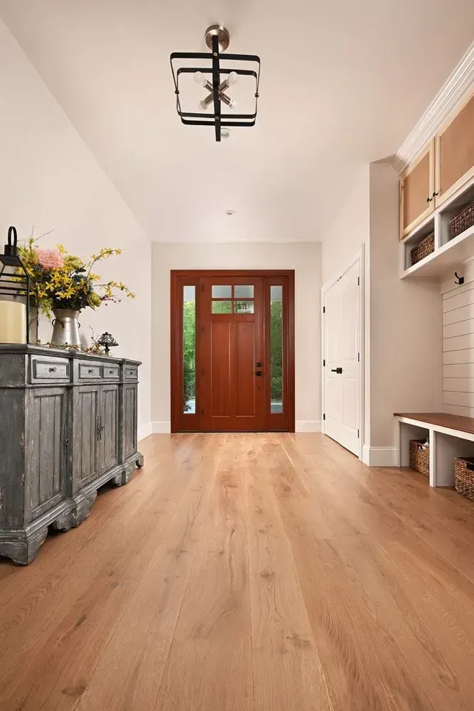 Wooden floored entryway with wood door, aged gray cabinet, and built-in bench and storage.