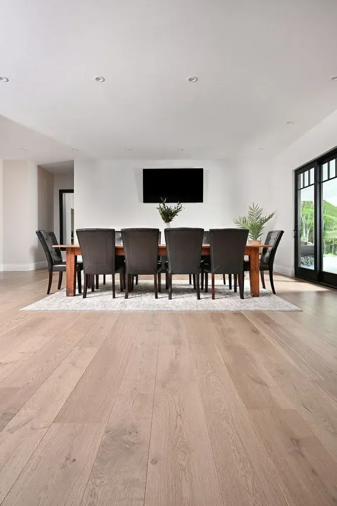 Dining room with a long wooden table, eight dark chairs, and a wall-mounted TV.