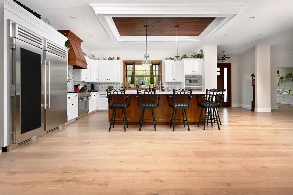 Spacious kitchen with light wood floors, white cabinets, a large stainless steel fridge.