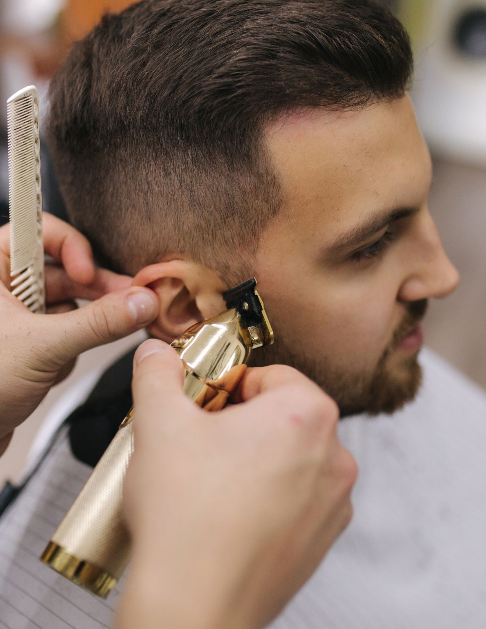 A man is getting his hair cut by a barber.