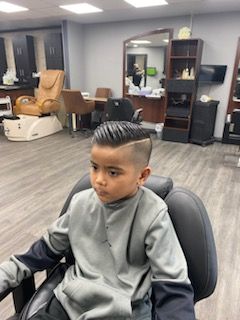 A young boy is sitting in a chair in a barber shop.