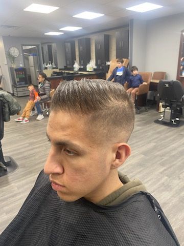 A man is getting his hair cut at a barber shop.