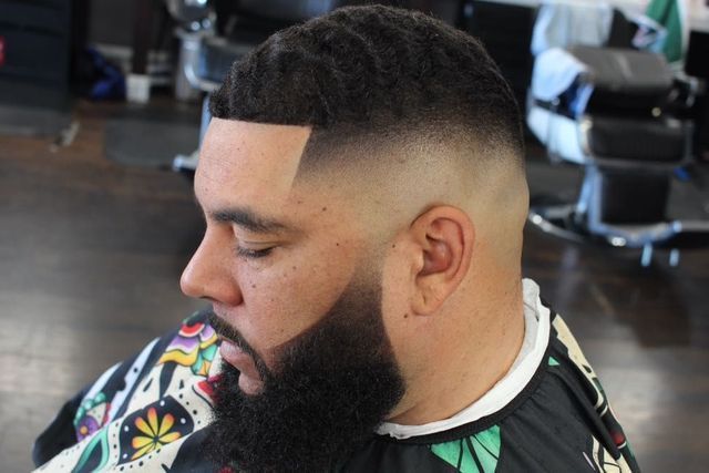 A man with a beard is getting his hair cut at a barber shop