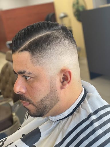 A man with a beard is getting his hair cut at a barber shop.