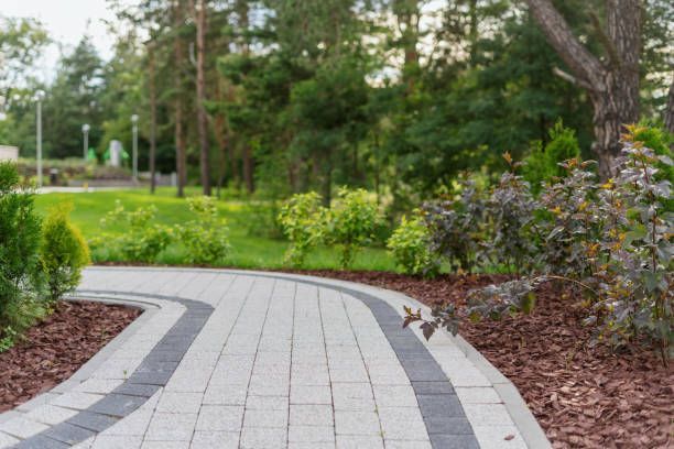 A brick walkway in a park surrounded by trees and bushes.