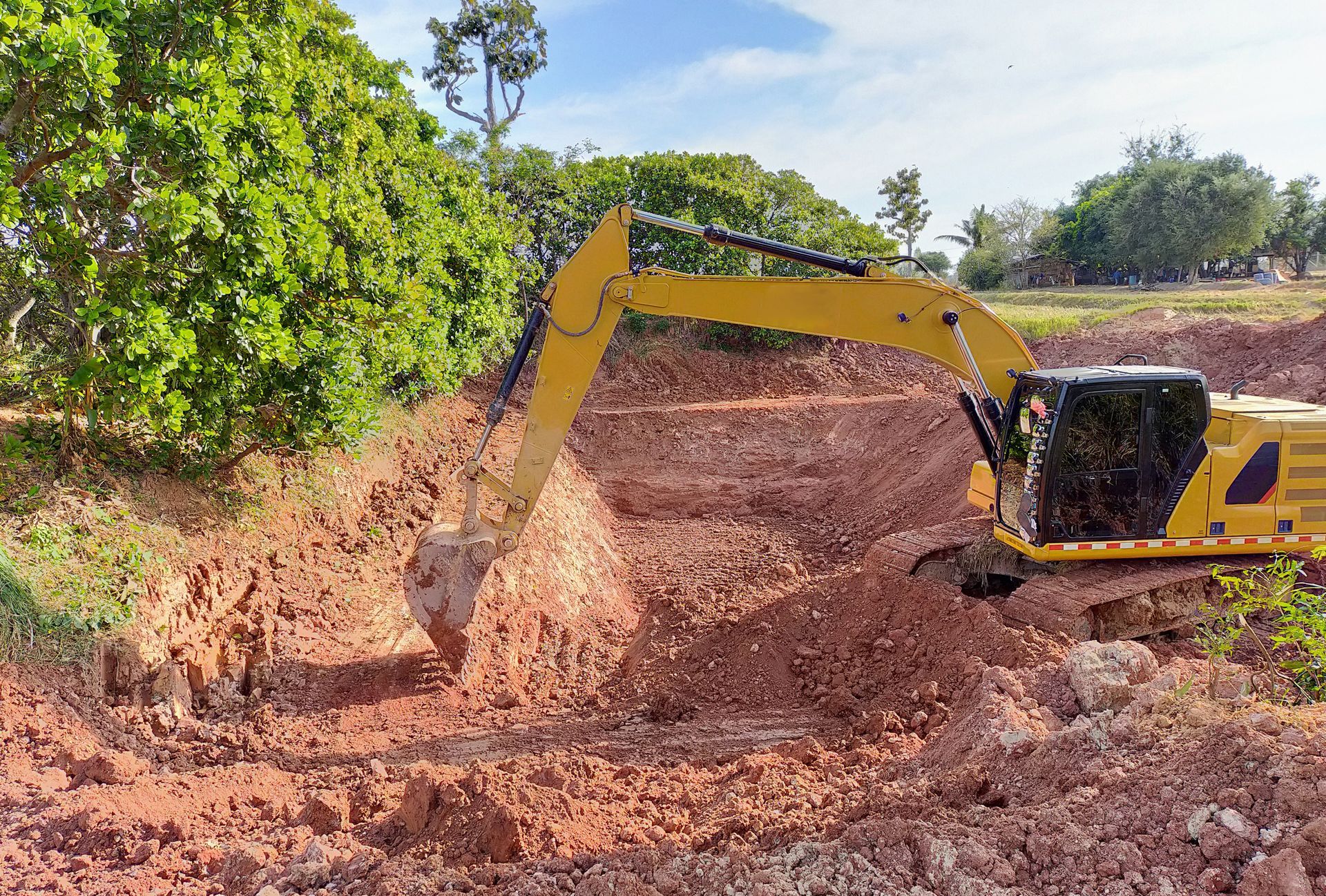 A yellow excavator is digging a hole in the dirt.