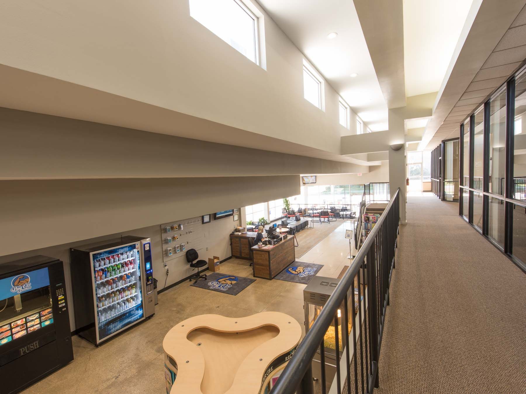 A long hallway with a table and a vending machine in a building.