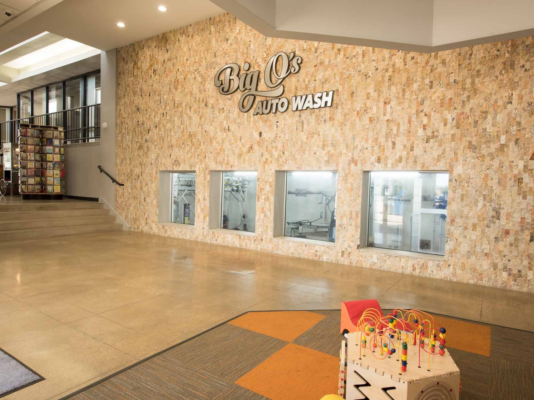 A large room with a large stone wall and a sign that says ' big o 's auto wash ' on it.