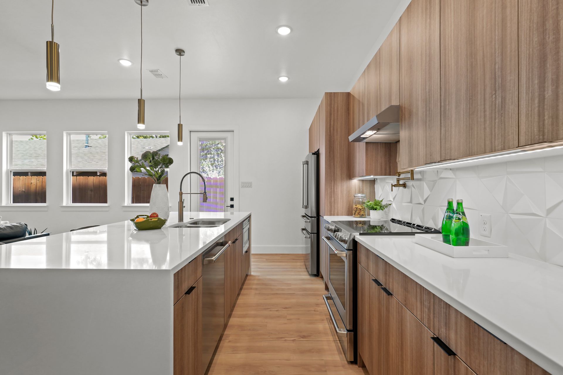 Modern kitchen with light wood cabinets, white countertops, and a large island. 