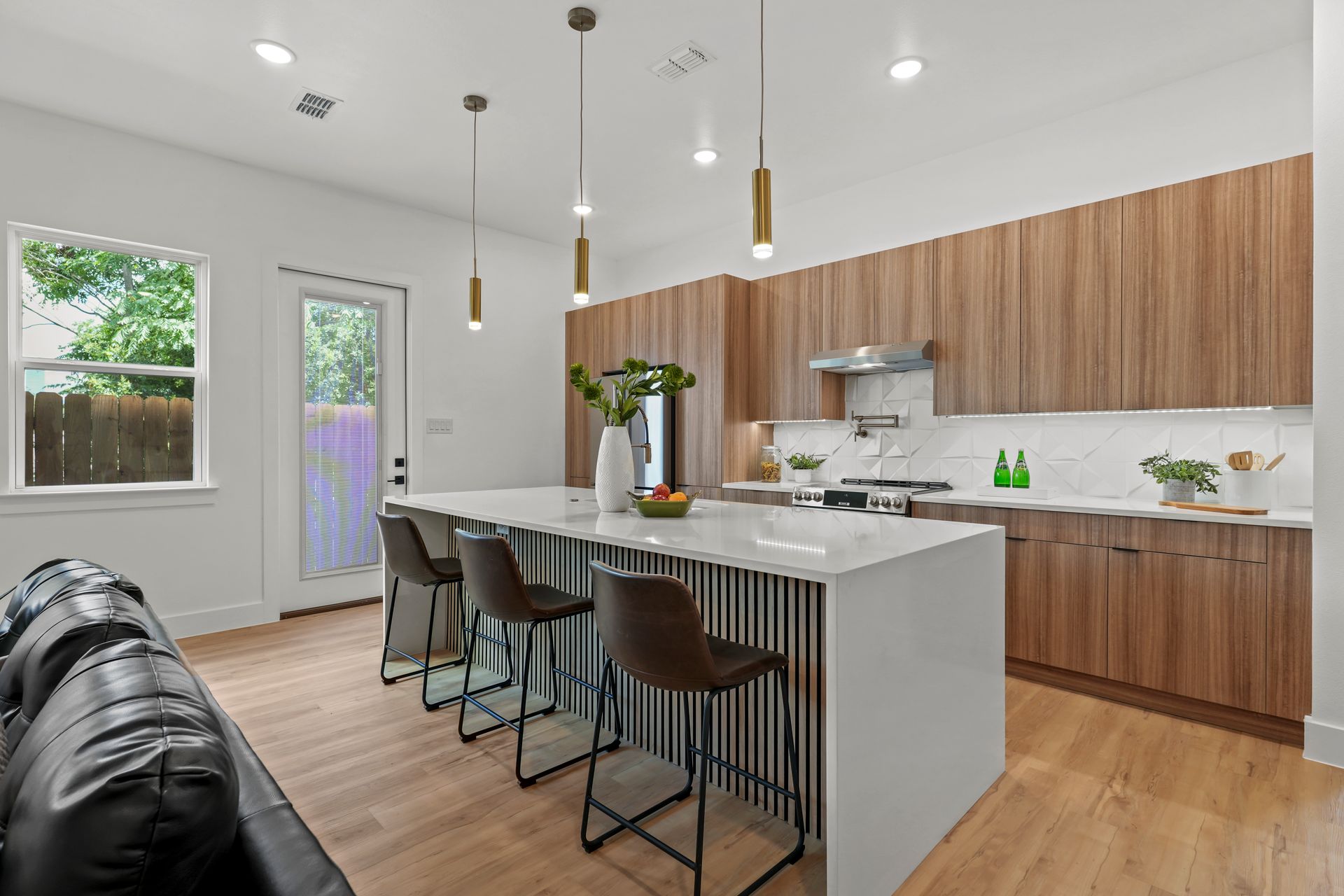 Modern kitchen with wood cabinets, white countertops, and a large island with bar stools.