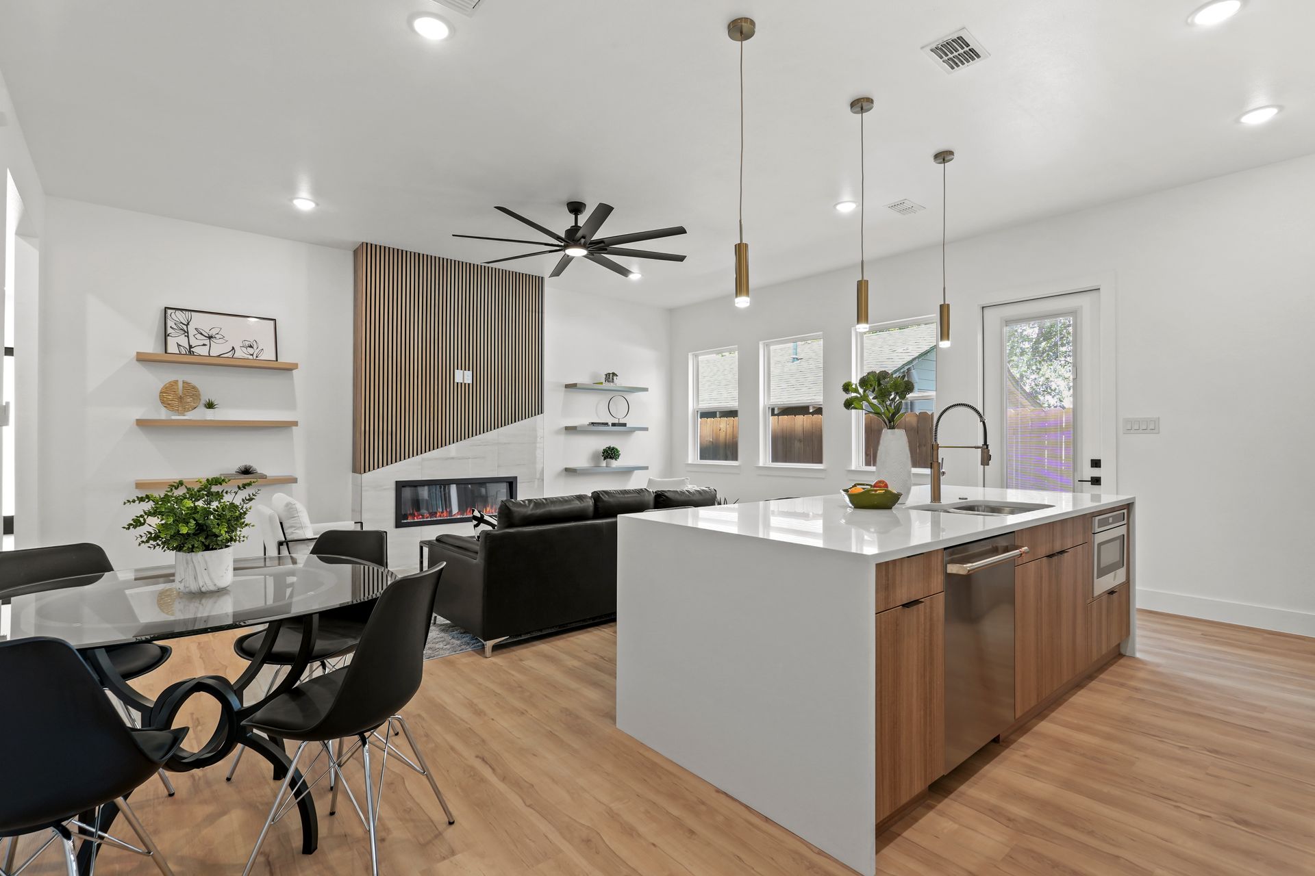 Open-concept living space with a kitchen island, dining table, and living area with fireplace. 