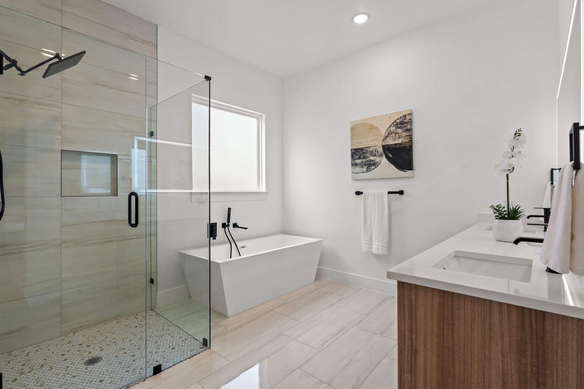 Modern white bathroom with a glass shower, soaking tub, and vanity with wooden cabinetry.