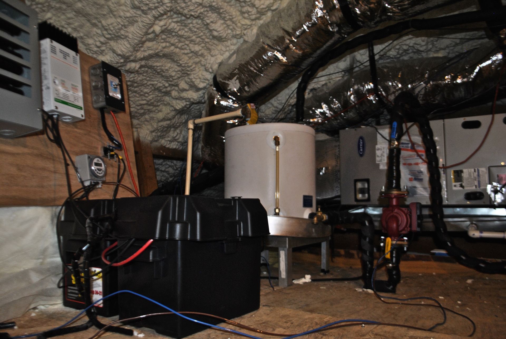 A water heater is sitting under a ceiling in a basement.