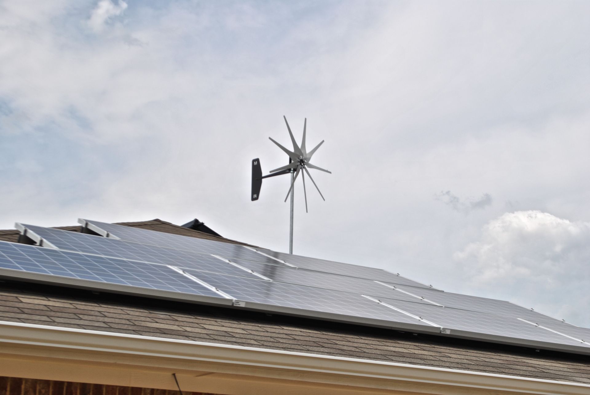 A wind turbine on top of a roof with solar panels