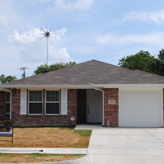 A brick house with a white garage door and a bench in front of it