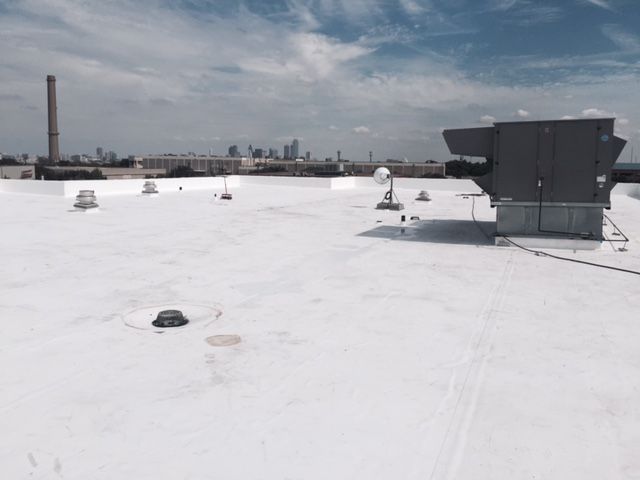 A white roof with a chimney on top of it and a city skyline in the background.