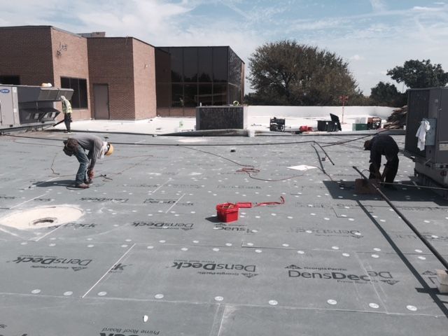 A group of men are working on a roof that says denspack on it