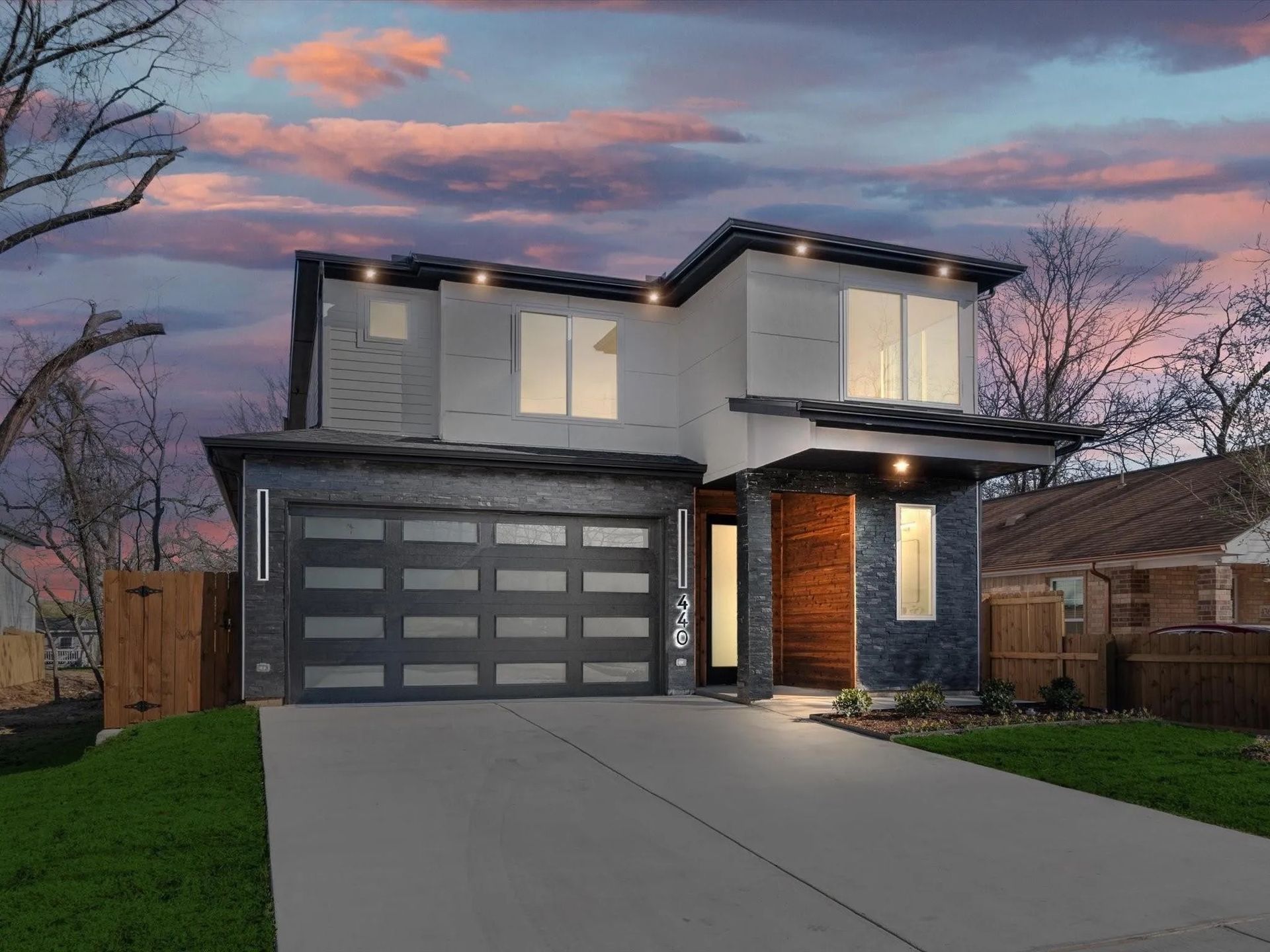 Modern two-story house with a gray garage door and a stone-accented entrance.