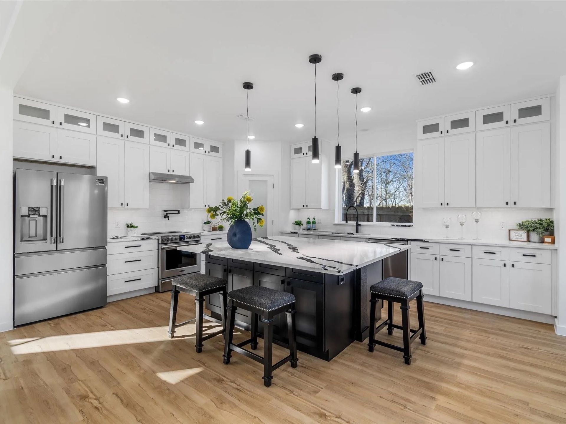 Modern kitchen with white cabinets, stainless steel appliances, and a dark island with seating.