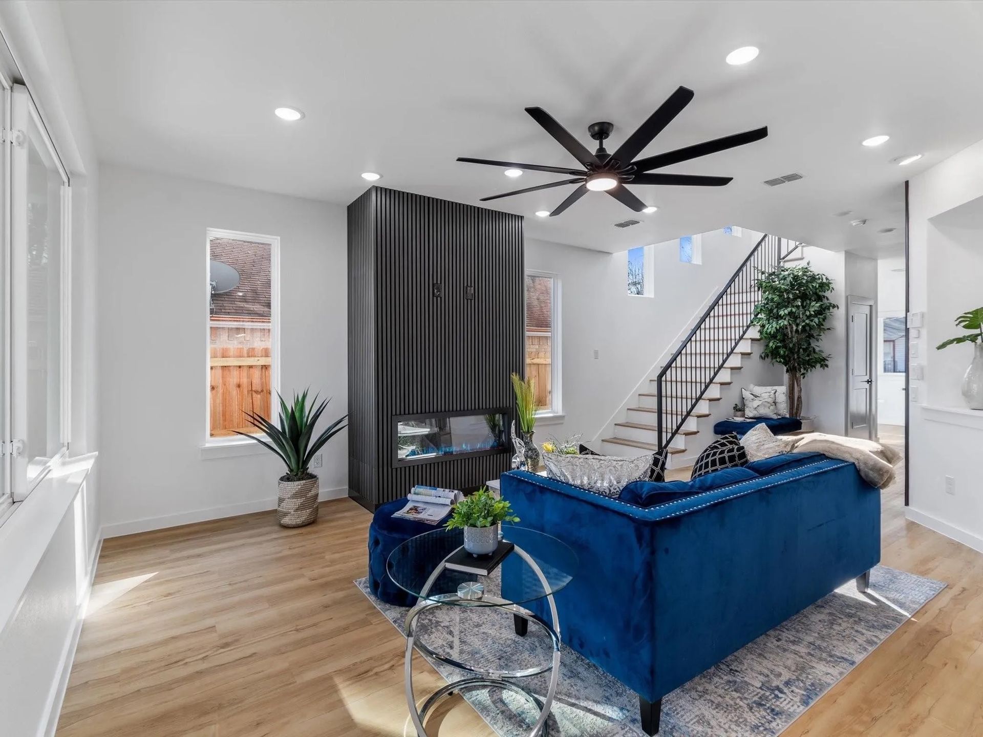 Living room with blue velvet couch, a black fireplace, and a staircase leading to the second floor.