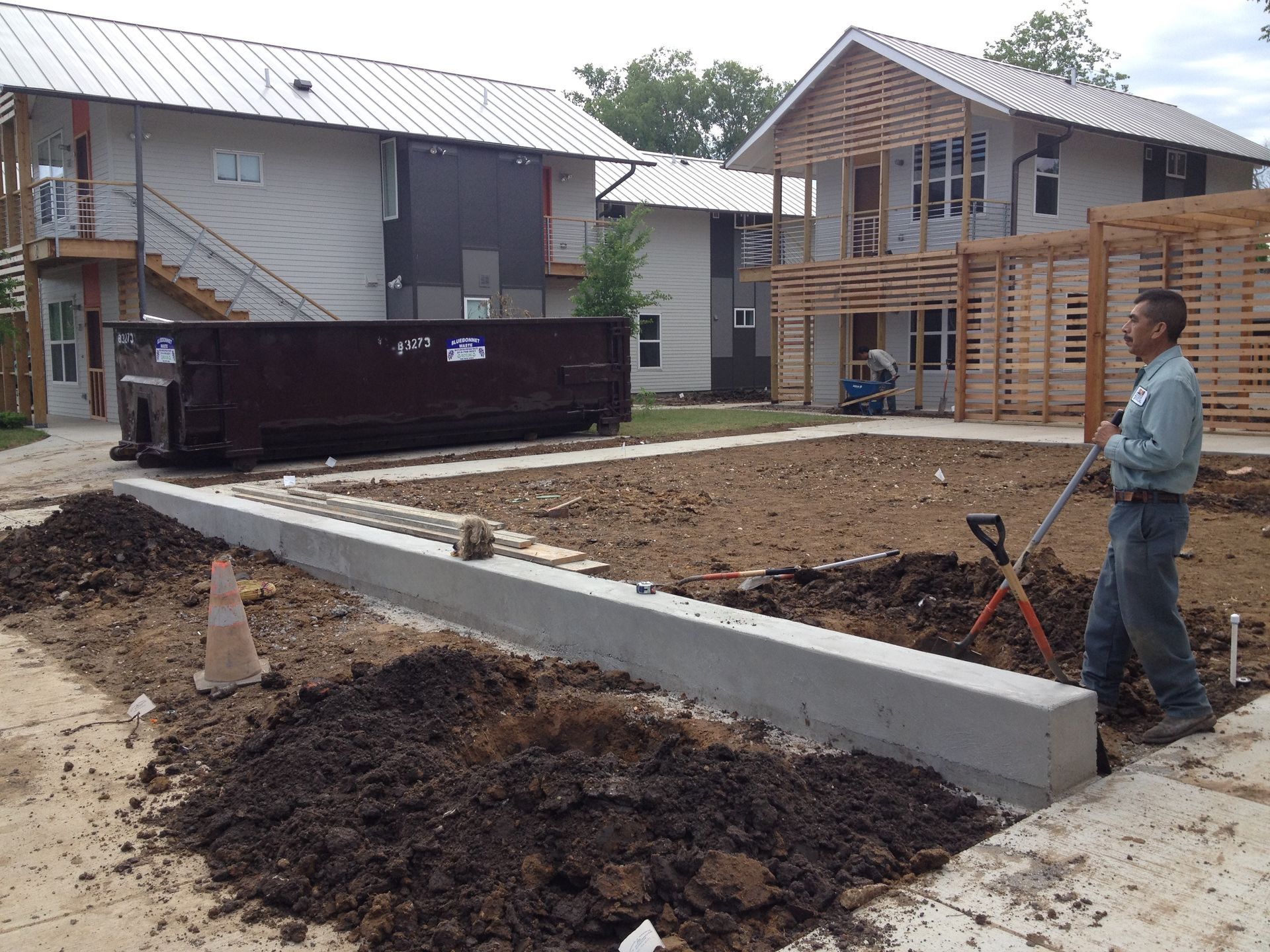 A man is digging in the dirt in front of a building.