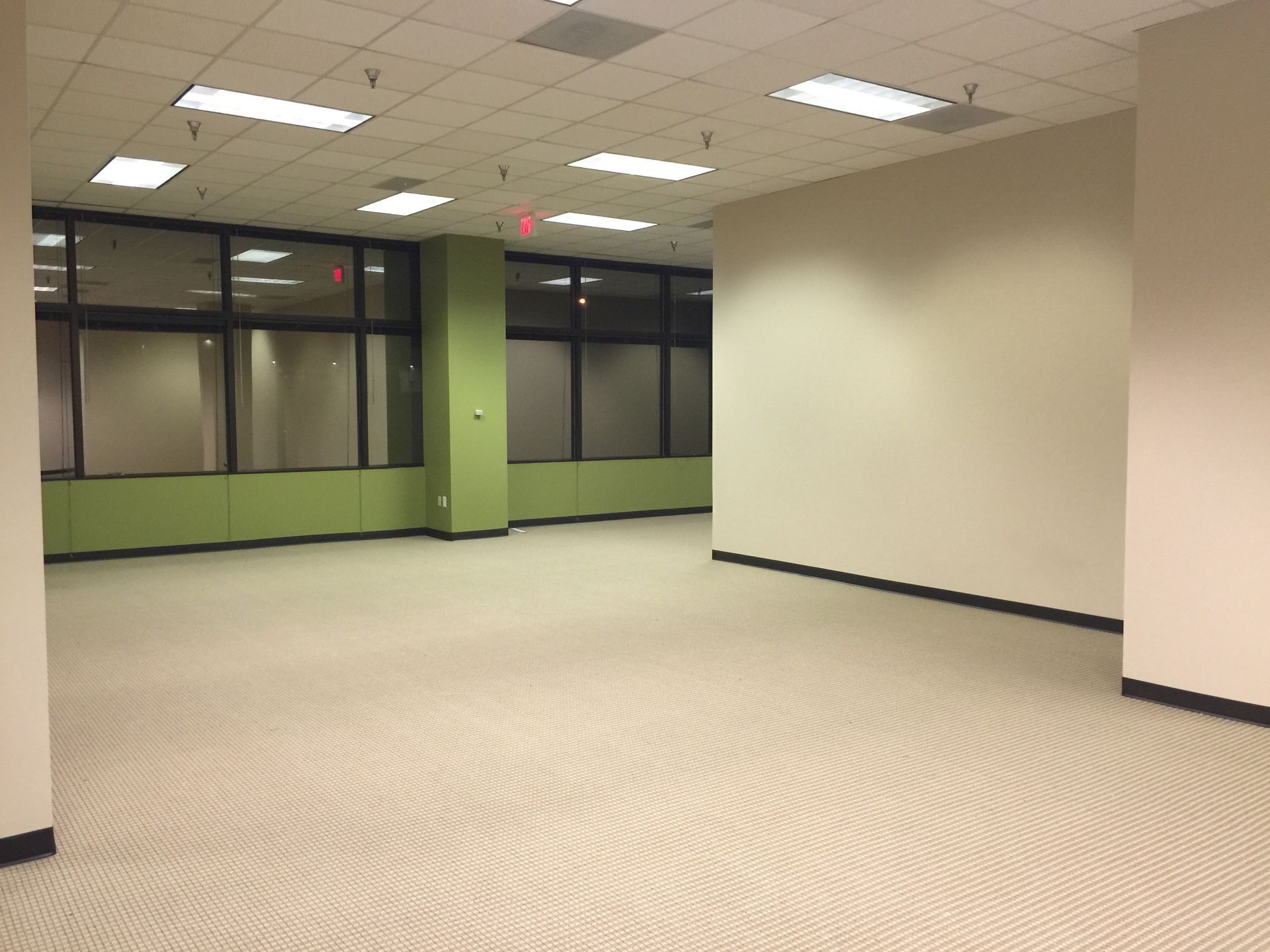 An empty room with a red exit sign on the ceiling