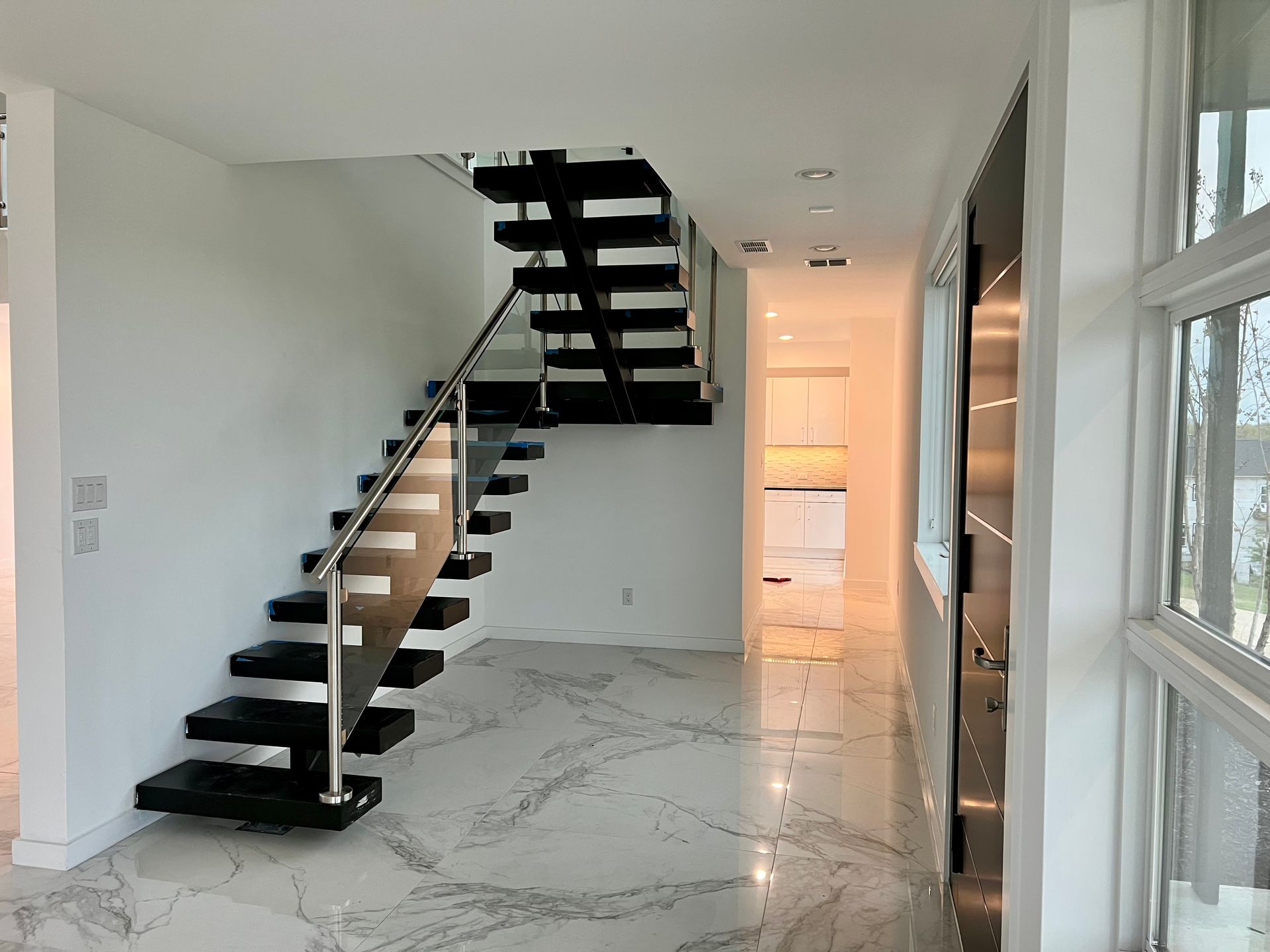 Modern interior with a floating staircase, black treads, and a stainless steel handrail. 
