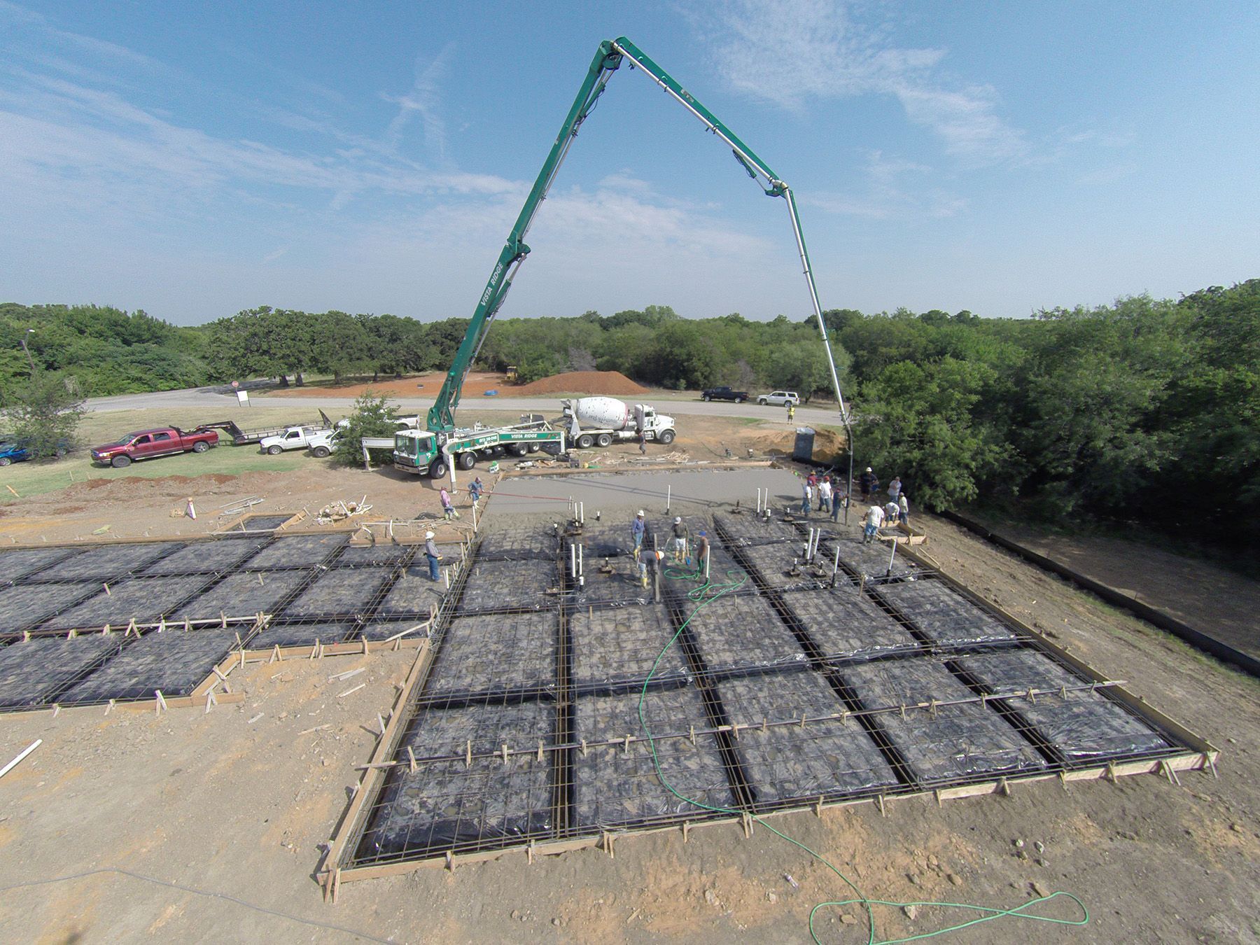 An aerial view of a construction site with a crane pouring concrete.