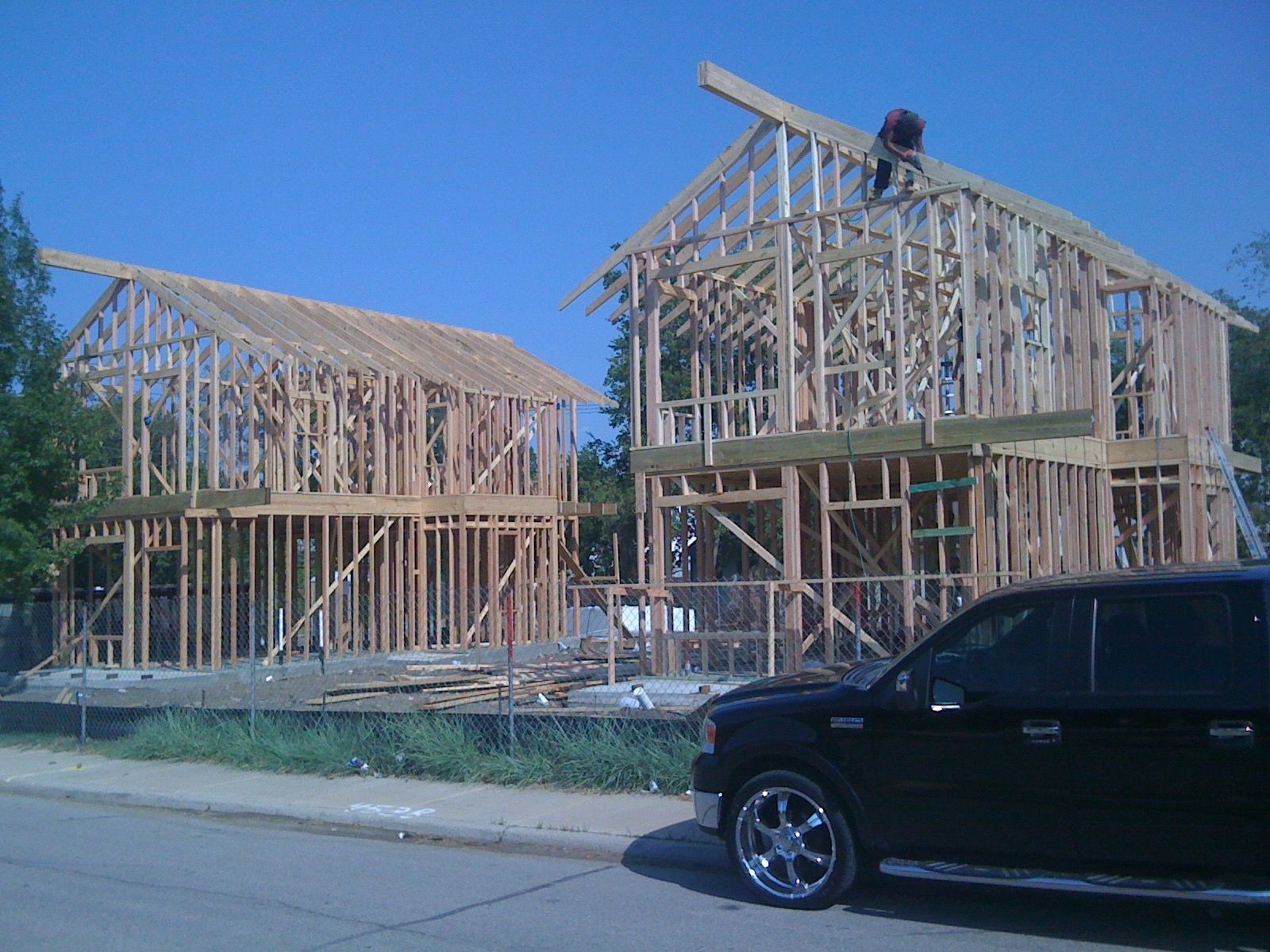 A black truck is parked in front of a house under construction