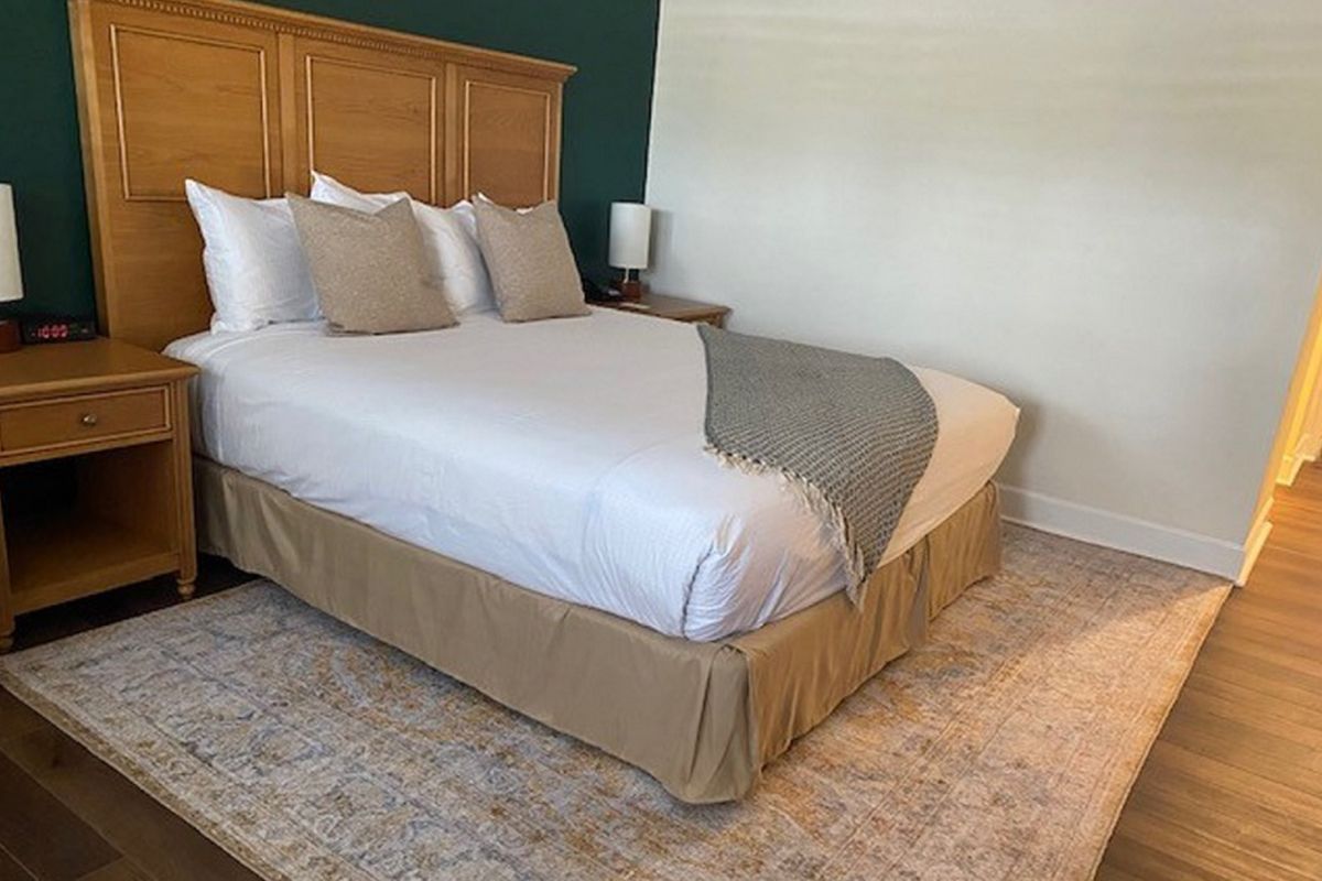 Bedroom with a bed, nightstands, rug, and green and white walls.