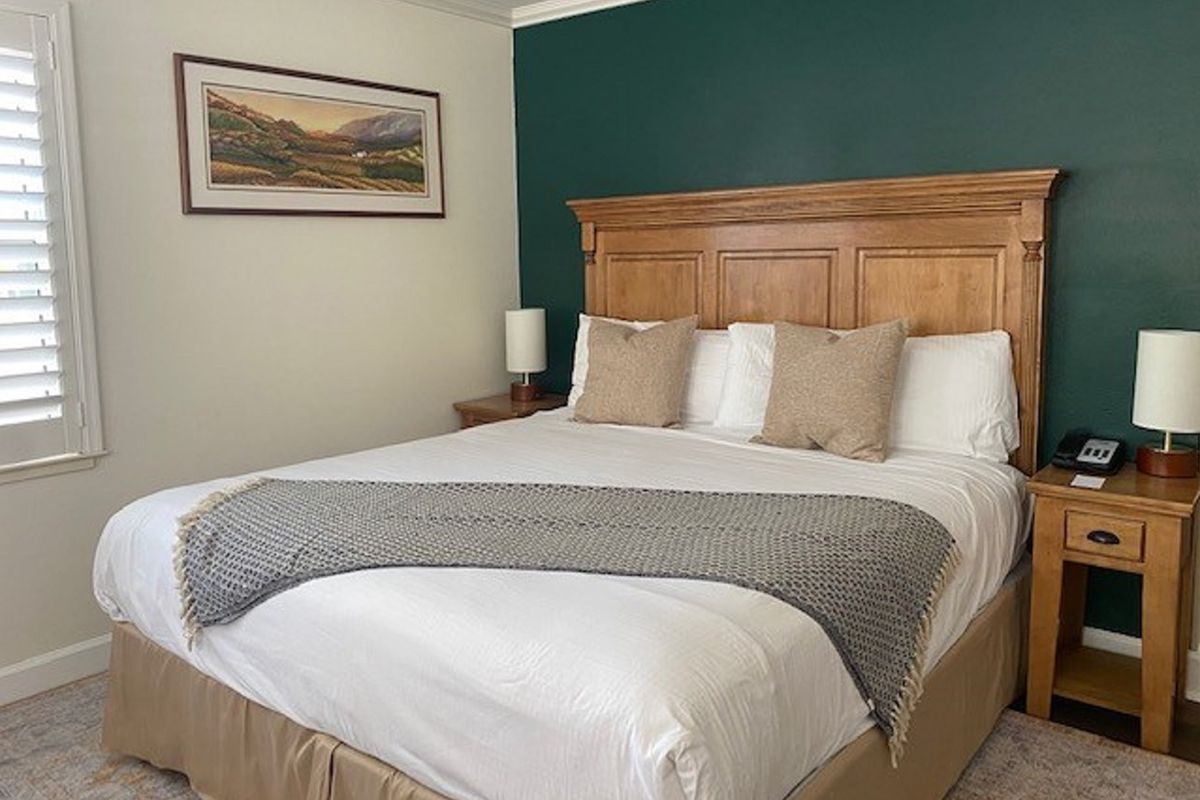 Bedroom with a large bed, wooden headboard, two nightstands, and dark green accent wall.
