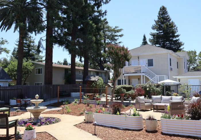 Bedroom with TV on dresser, desk with lamp, chair, and art on the wall.