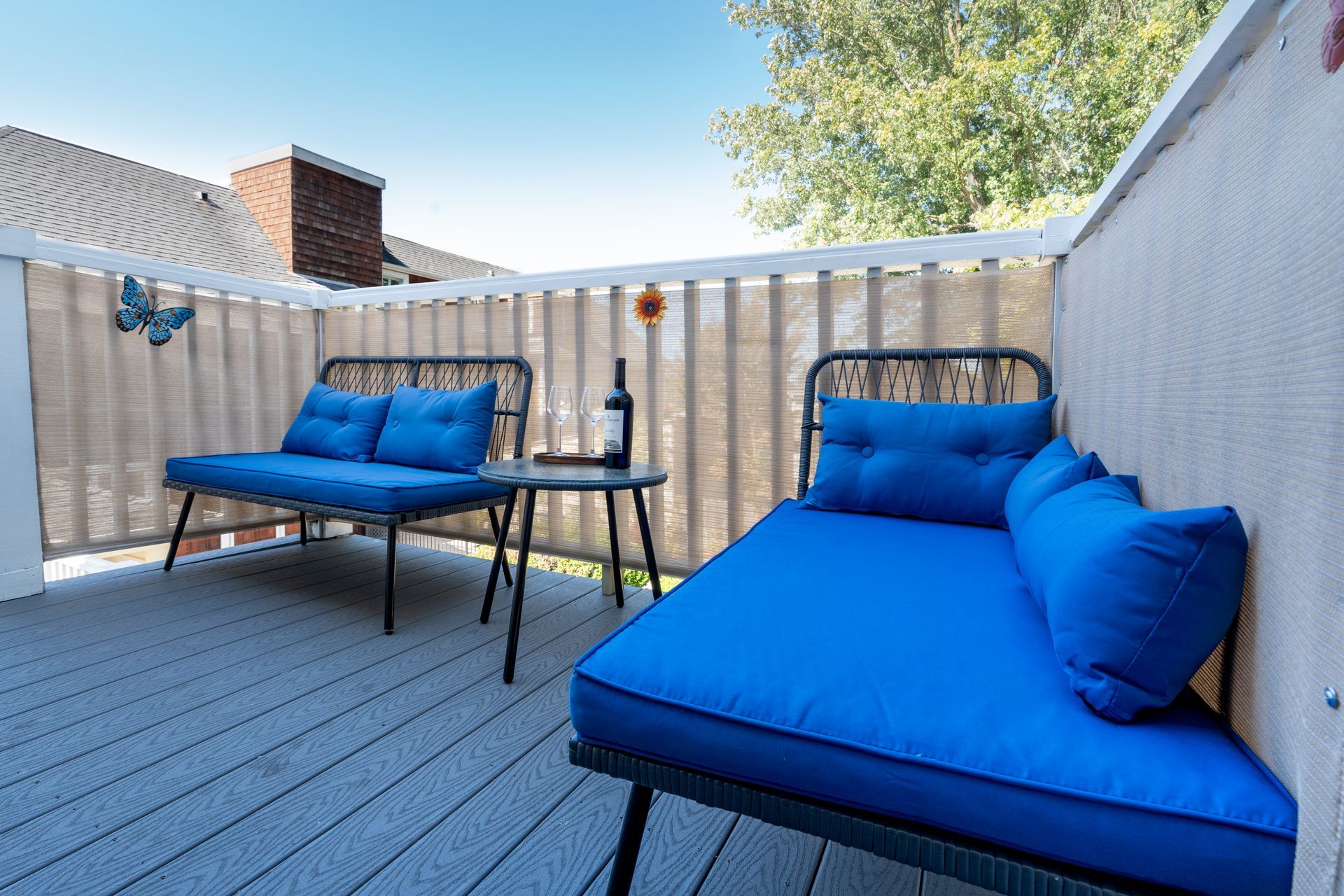 Outdoor patio with blue cushioned seating, small table, and privacy screen.