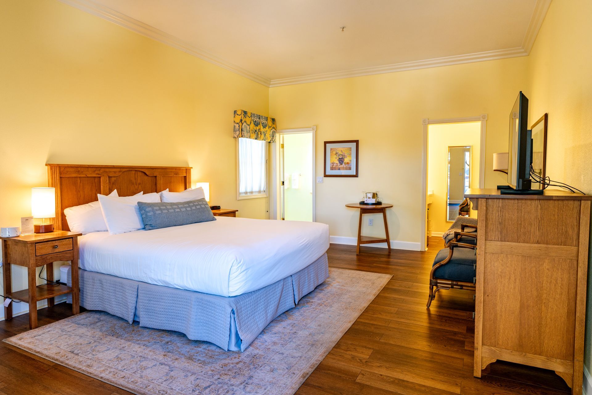 Bedroom with a large bed, wooden furniture, and light yellow walls.