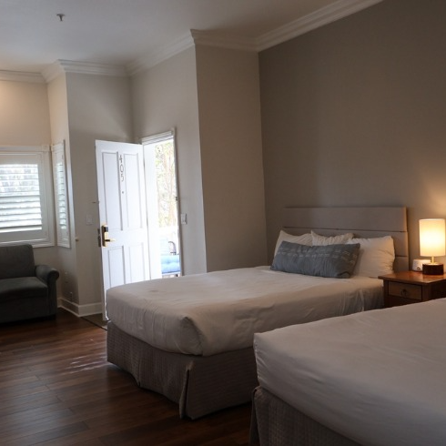 Two twin beds in a room with a doorway and a small couch.