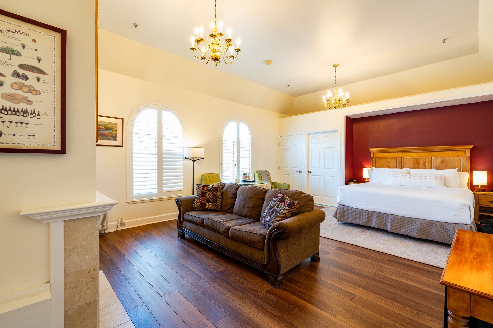 Hotel room with a brown sofa, a large bed, and wooden floors.